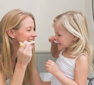 Happy mother and daughter brushing their teeth